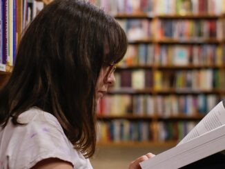 Foto di una ragazza che legge un libro in biblioteca