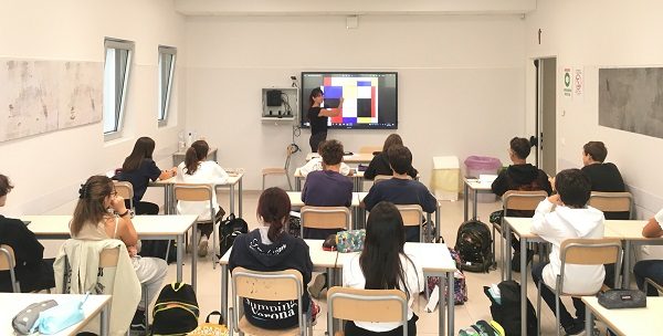 una classe dell'Acof di Busto Arsizio vista dal retro con una professoressa che spiega alla lavagna