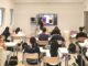 una classe dell'Acof di Busto Arsizio vista dal retro con una professoressa che spiega alla lavagna